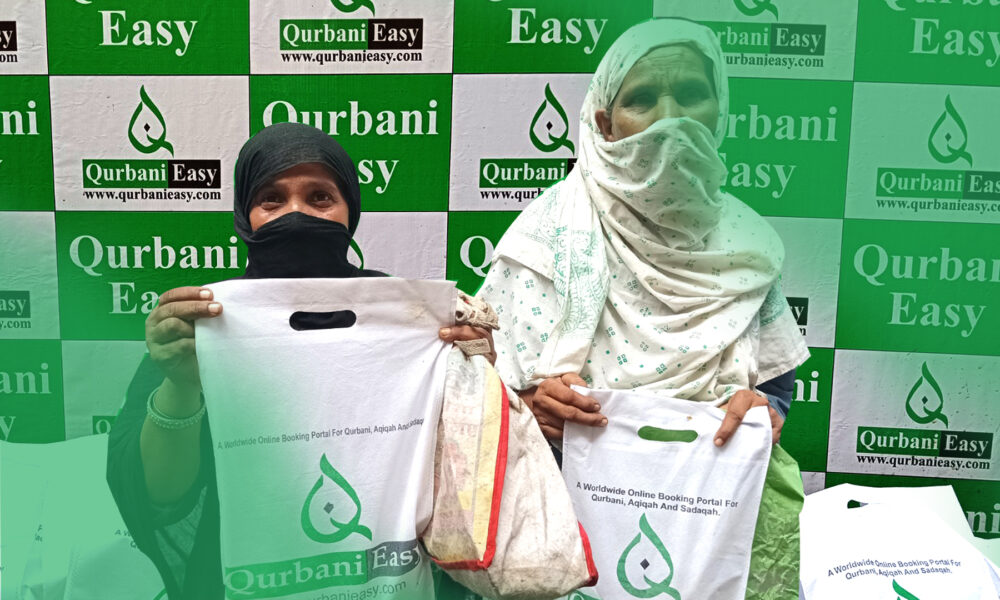 This image showcases two women holding boxes distributed by Qurbani Easy, a platform dedicated to facilitating Qurbani services. The background features banners promoting "Qurbani 2024," highlighting the organization's commitment to providing fresh meat to deserving individuals. The scene reflects Qurbani Easy's efforts to ensure that the blessings of Eid-ul-Adha reach those in need